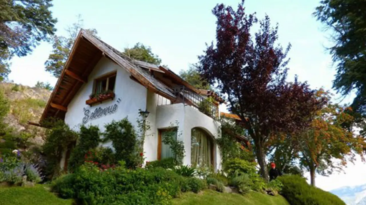 Chalé em estilo alpino rodeado por vegetação exuberante, hospedagem charmosa na região de Villa La Angostura, Argentina.