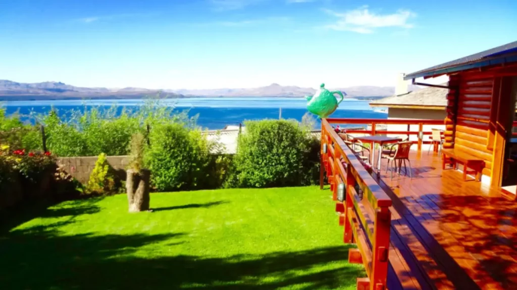  Varanda com deck de madeira e vista panorâmica para lago azul na Patagônia, ideal para relaxar em meio à natureza.