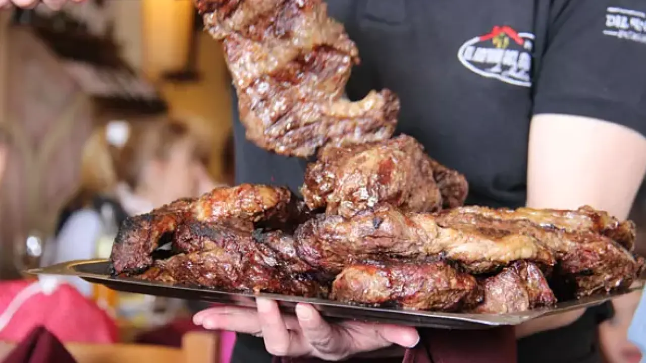 Prato farto de carnes assadas típico de uma parrillada argentina sendo servido em restaurante de Bariloche.