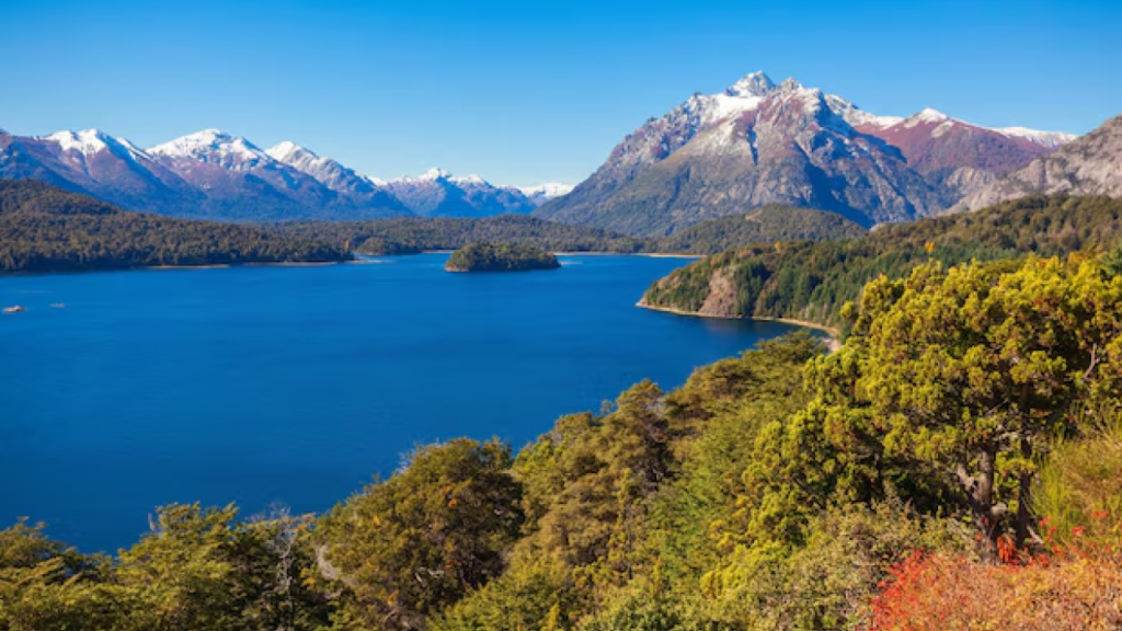 Paisagem do Parque Nacional Nahuel Huapi em Bariloche com lago azul, floresta nativa e montanhas nevadas.