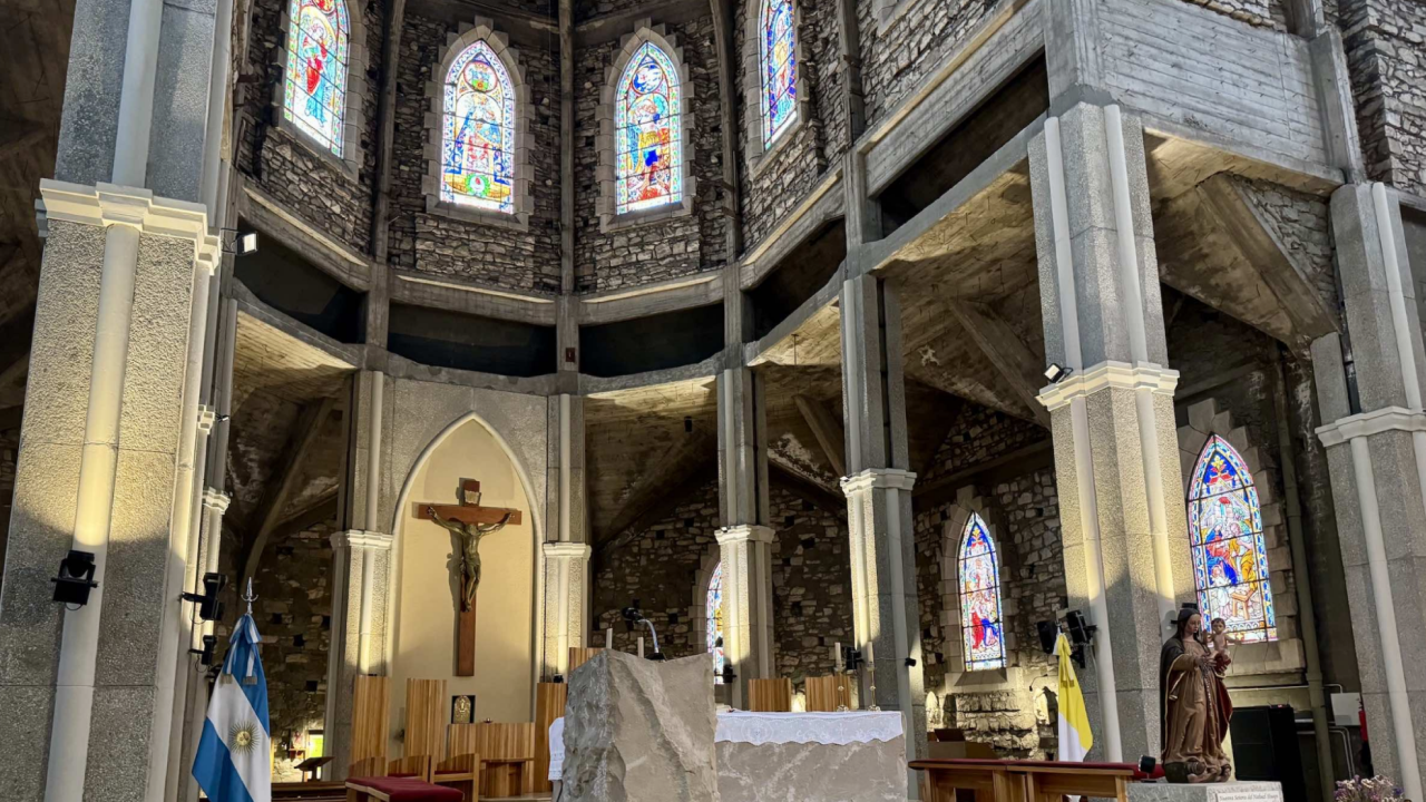 Interior da Catedral de Bariloche com vitrais coloridos e altar central com crucifixo.