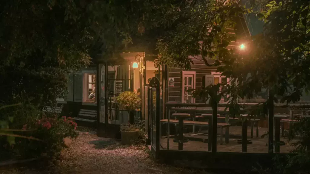 Fachada de restaurante rústico em Bariloche iluminado à noite, cercado por árvores.