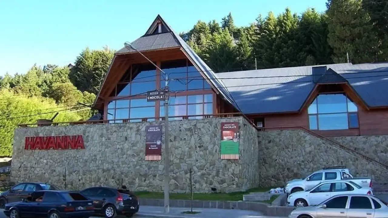 Prédio de pedra e madeira da Havanna em Bariloche, onde funciona o Museu do Chocolate, com carros estacionados ao redor.