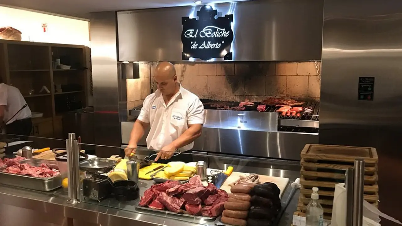 Churrasqueiro selecionando cortes na parrilla aberta do El Boliche de Alberto, Bariloche