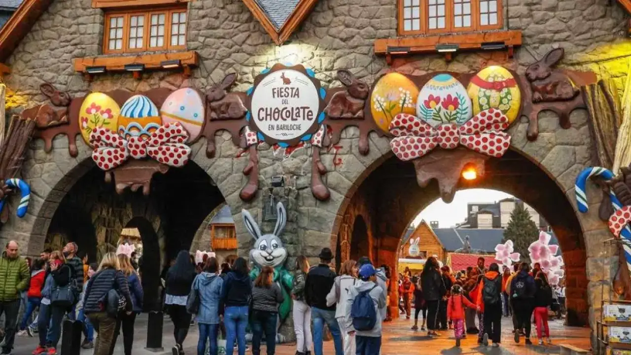Entrada principal decorada da Fiesta del Chocolate em Bariloche, com ovos de Páscoa gigantes e coelho de pelúcia recepcionando os visitantes.