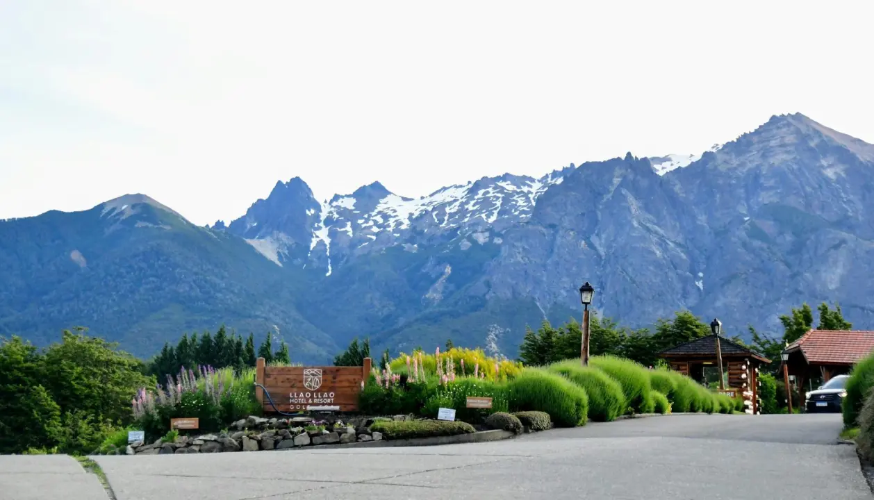 Majestosas montanhas cobertas de neve ao fundo, cercadas por vegetação exuberante.