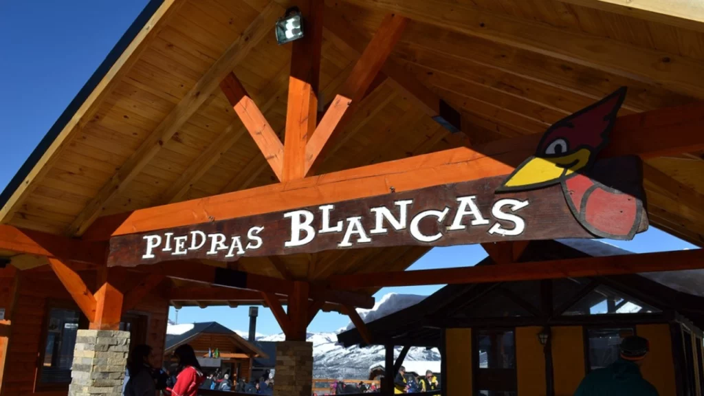 Entrada do parque de inverno Piedras Blancas, localizado em Bariloche, Argentina, com sua arquitetura rústica e o icônico letreiro de madeira.