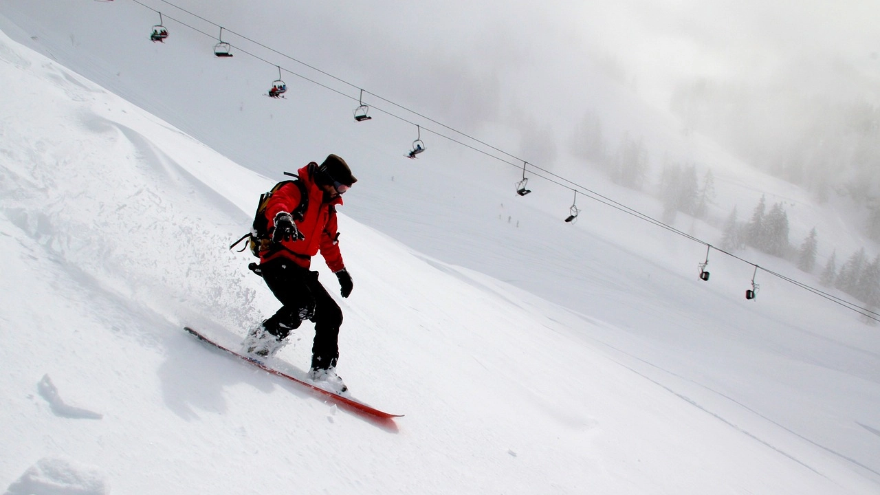 Esquiador descendo uma pista de esqui coberta de neve com teleféricos ao fundo em um dia nublado em San Carlos de Bariloche.