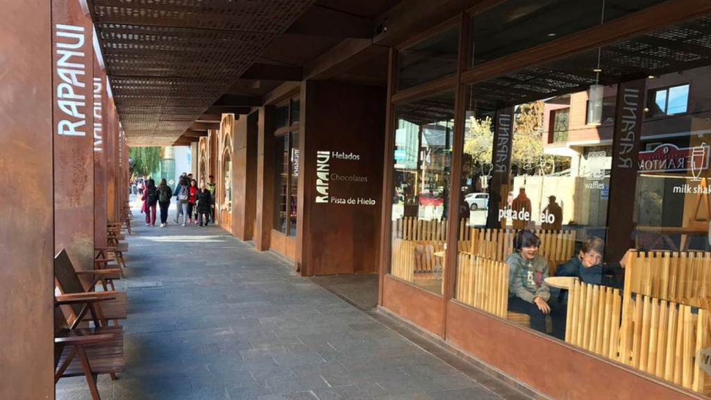 Fachada da chocolateria Rapa Nui em Bariloche, com destaque para a vitrine colorida e movimentação de turistas.