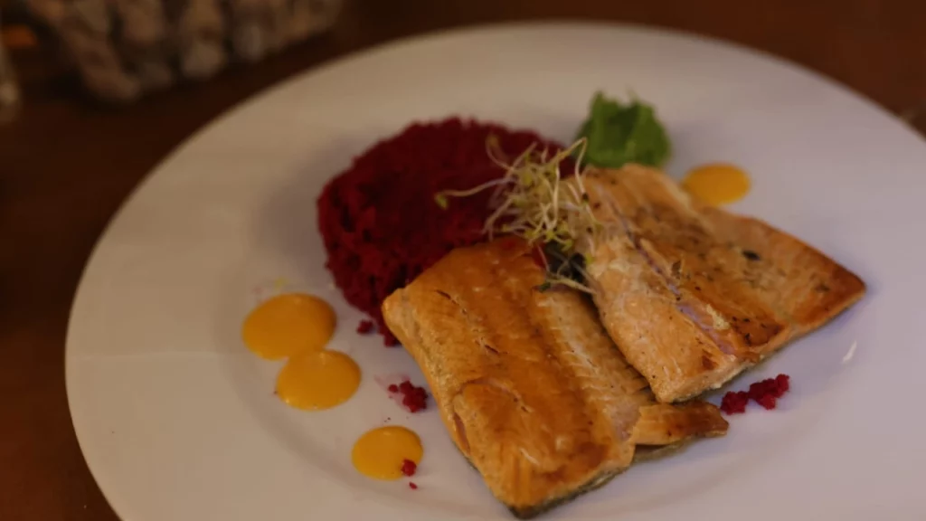 Prato gourmet servido no restaurante La Cueva no Cerro Catedral, em Bariloche, apresentando filé de peixe grelhado acompanhado de purê de beterraba e molho cítrico. Uma das especialidades típicas da culinária argentina na região da Patagônia.