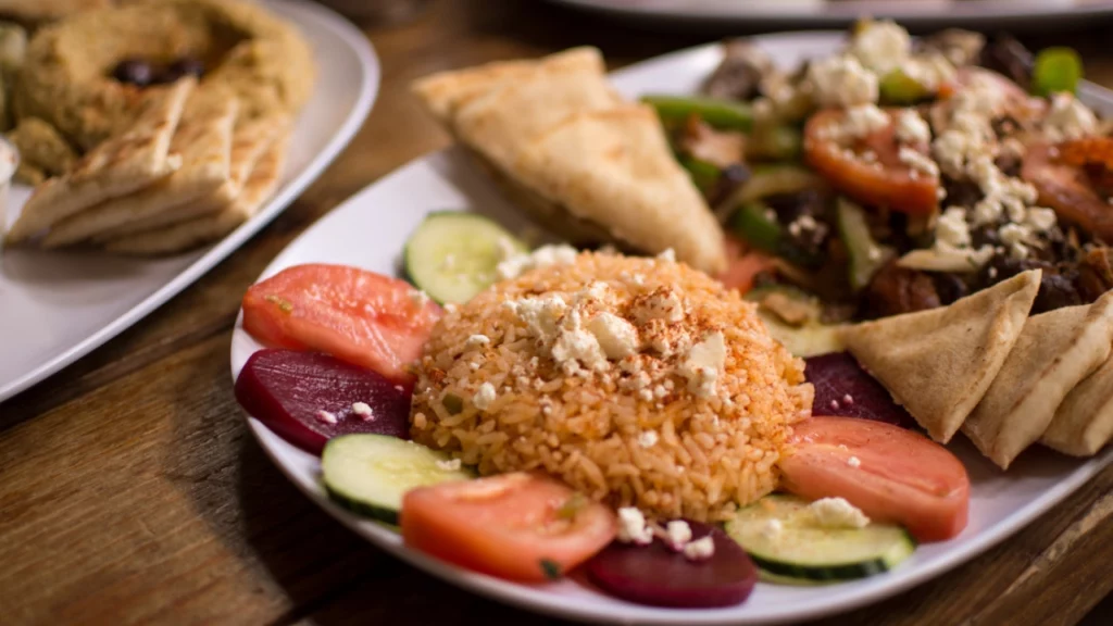 Prato com arroz, salada, fatias de tomate, pão sírio e outros acompanhamentos típicos servidos em um restaurante participante do festival.