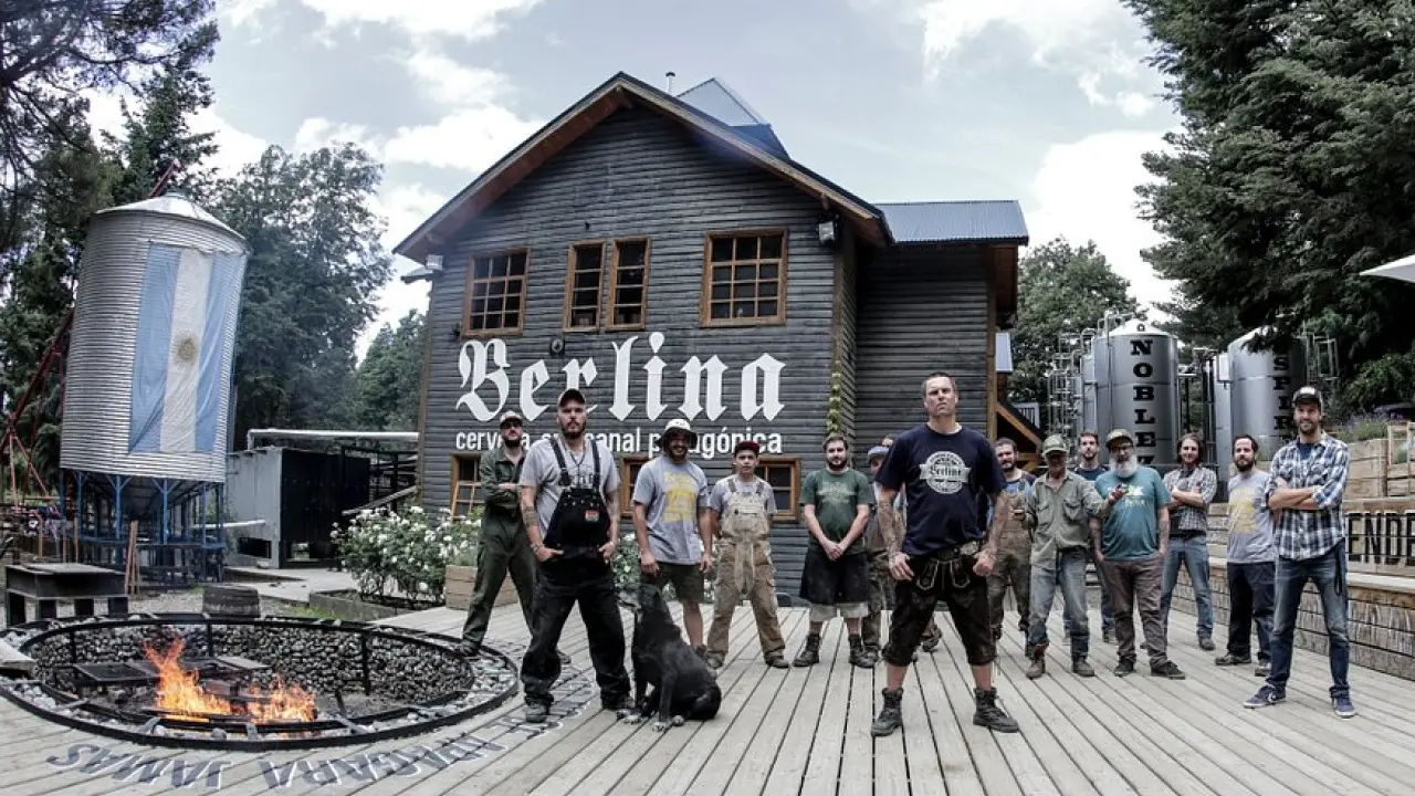 Fachada de madeira da Berlina com equipe posando e tanques de produção ao fundo.
