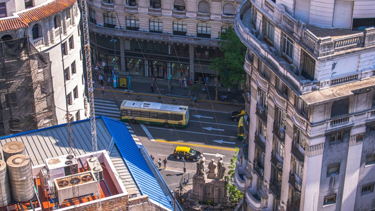 Vista aérea de Buenos Aires com ônibus e táxis circulando pelas ruas, destacando a movimentação urbana e a arquitetura característica da cidade.