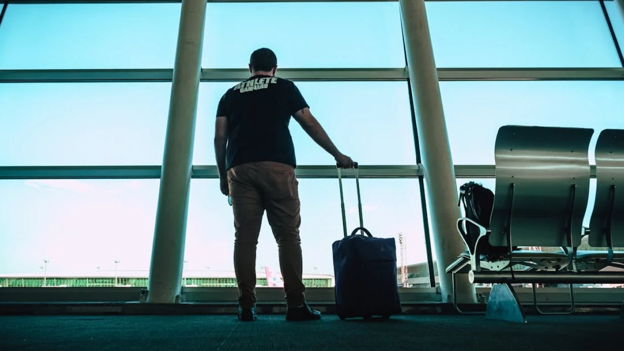 Viajante de costas com uma mala, esperando no aeroporto, simbolizando a importância do planejamento e das precauções antes de viajar para a Argentina.