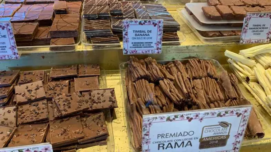 Vitrine com chocolates artesanais premiados em Bariloche, incluindo chocolate em rama e variedades com doce de leite.